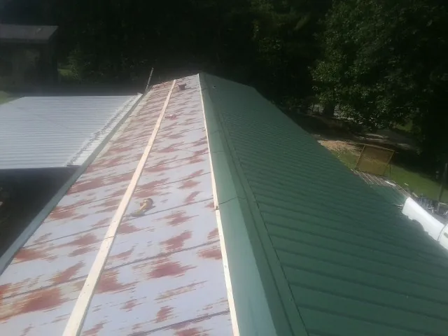 Old rusted panels beside newly installed green metal roofing — Wind Damage Roof Repair by Roofing Brothers in White Bird