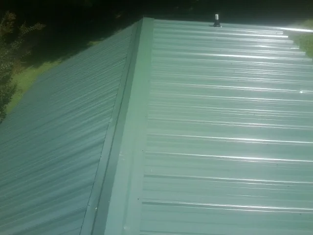New green metal panels meeting at the ridge of a roof — Flat Roof Repair work by our crew in White Bird