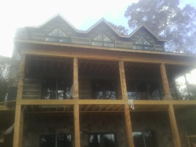 Dormers and porch framing on a large log home under construction — Roof Coating work by our crew in White Bird