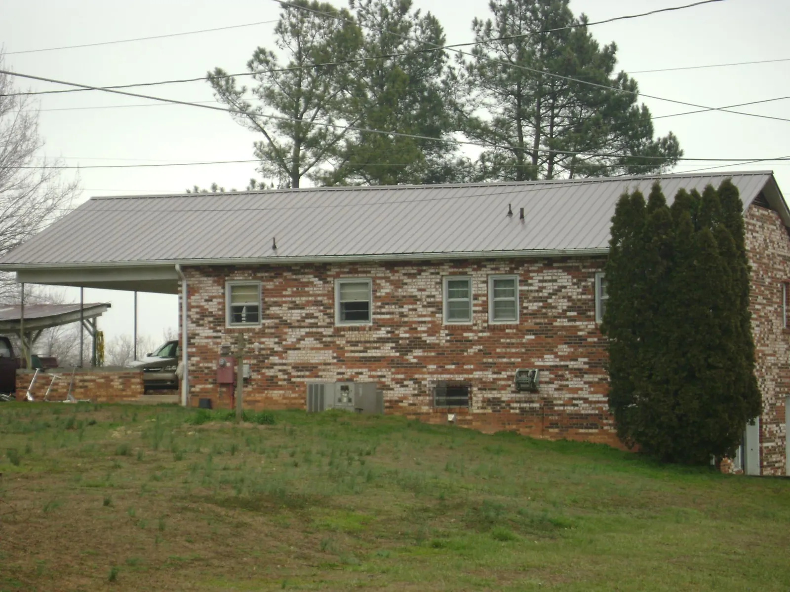 Gray metal roof on a brick split level home with a carport in White Bird