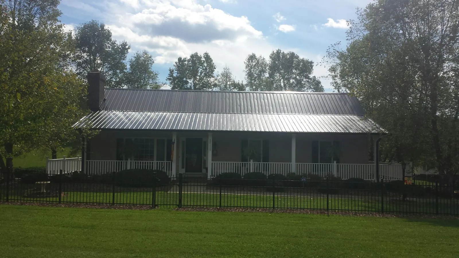 Gray metal roof on a brick ranch with a full width front porch — Gutter Guard Installation work by our crew in White Bird