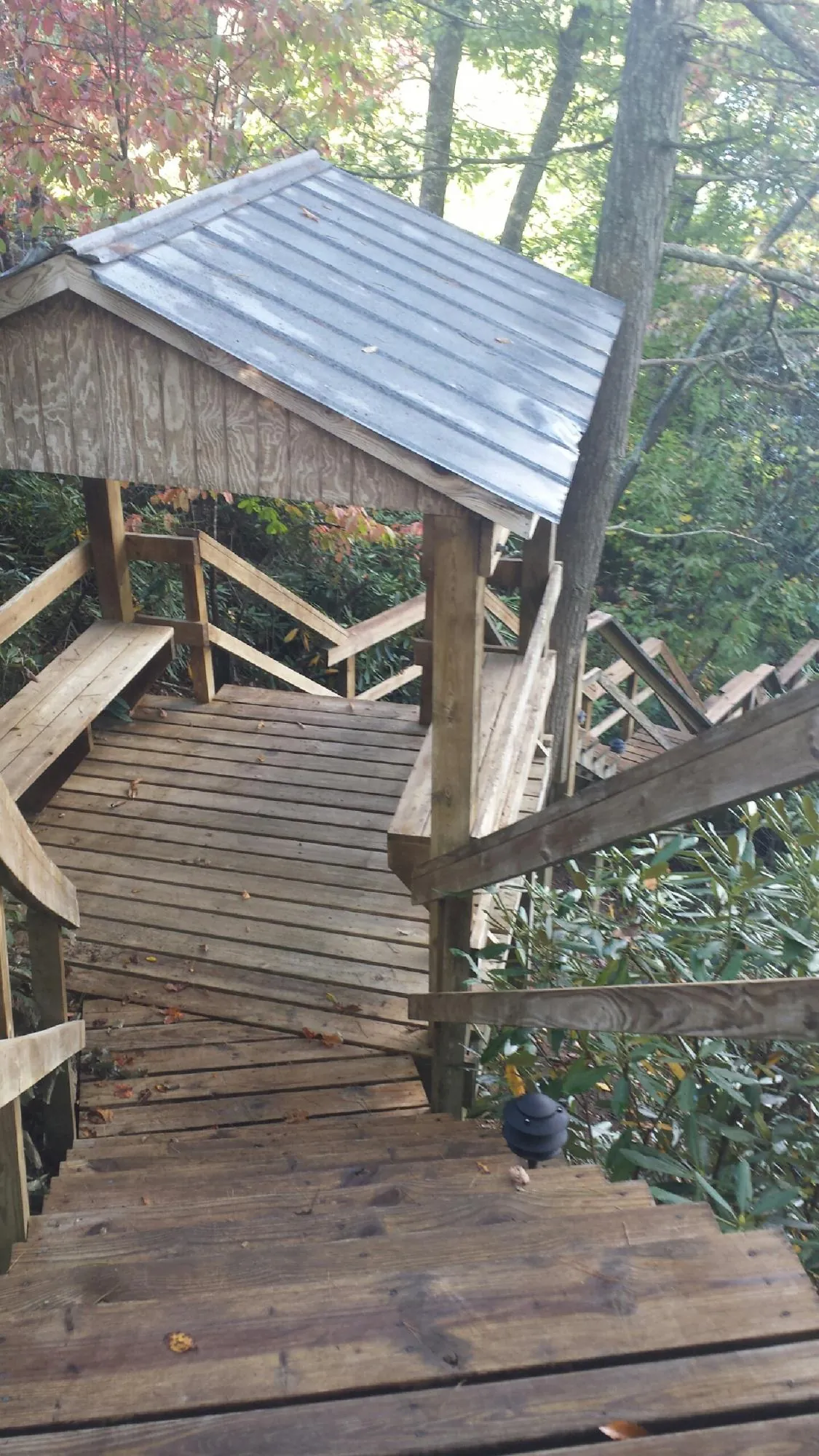 Metal roofed shelter over wooden steps on a wooded walkway — Skylight Repair & Installation work by our crew in White Bird