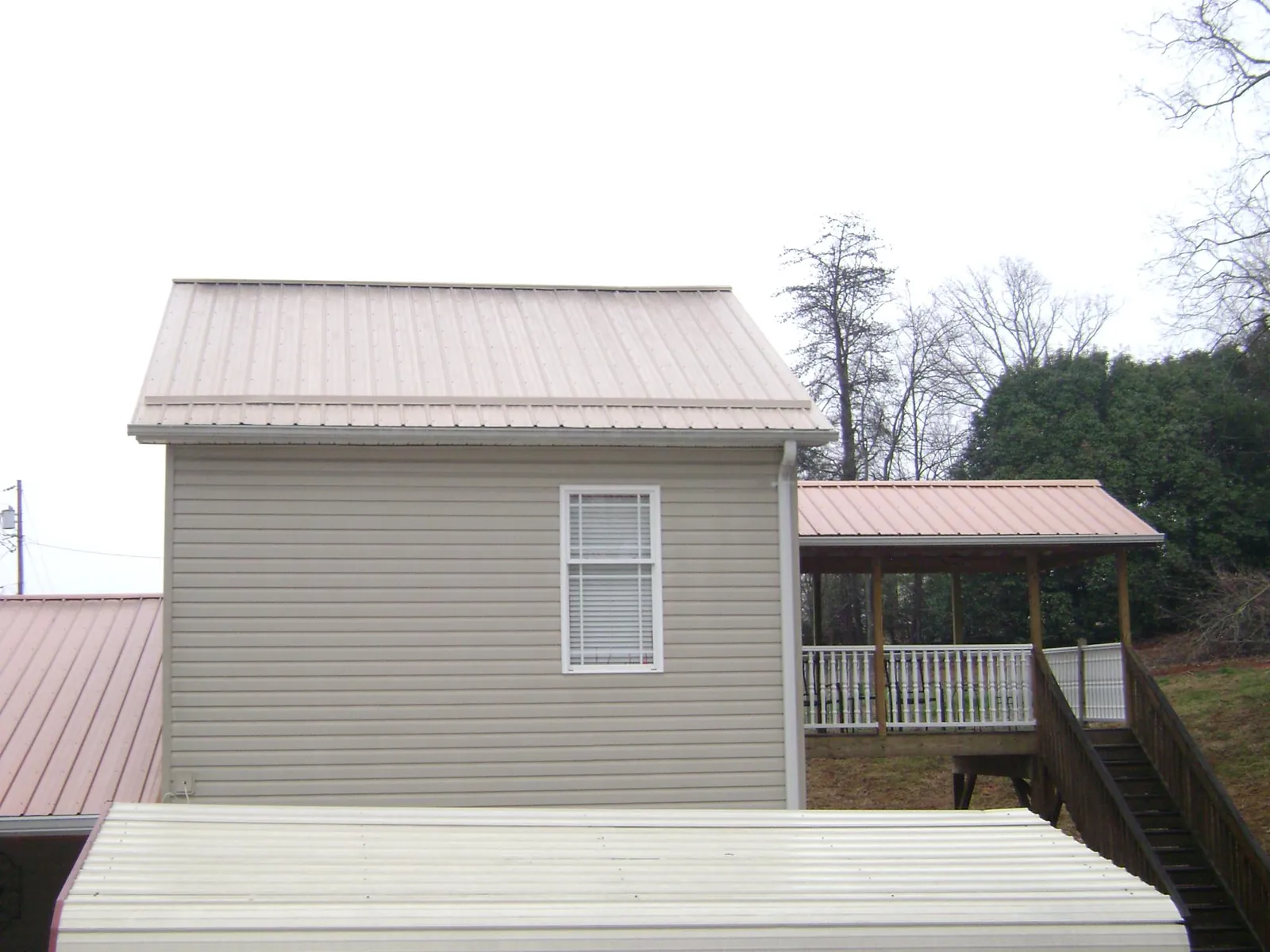 Tan metal roofs on a two story addition and attached porch, from a Roof Replacement job in White Bird